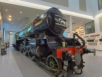 Steam locomotive on display in a spacious exhibition area with large windows at Danum Library