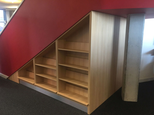 Custom shelving built around a structural column under a staircase at Oldham Library