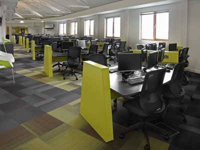 Bright green study desks with black ergonomic chairs in a modern study area at Boots Library