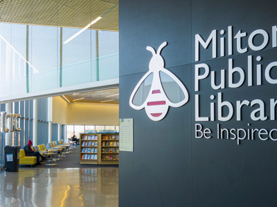 Bright yellow lounge chairs and browsing shelves in a public library seating area at Sherwood Library