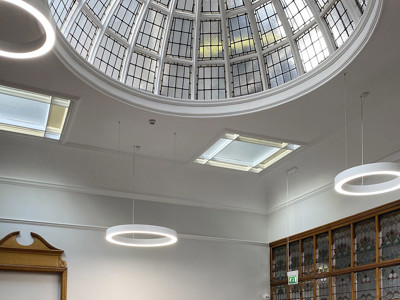 Circular glass dome with intricate detailing above a study area featuring modern workstations and pink chairs at Armley Library