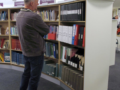 A man browsing through neatly arranged archival boxes and folders in a local studies area at Newark Local Studies