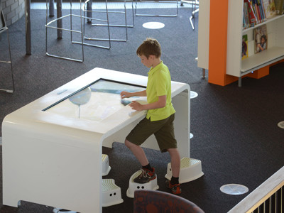 Interactive touchscreen table with a child engaged in digital exploration at Southwater Library