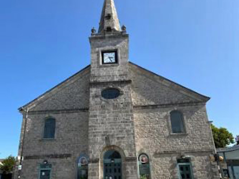 Stone façade with a tall steeple and clock at the entrance of St Aubyn Library Church at St Aubyn Library Church