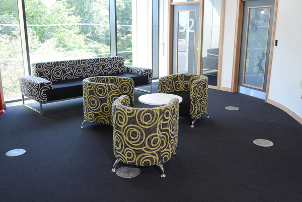Circular patterned tub chairs and a patterned sofa around a white coffee table in a social seating area at Southwater Library