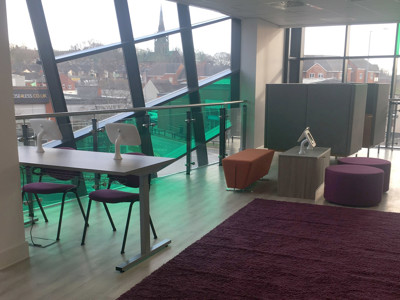 Contemporary study tables and colourful seating areas with purple and orange poufs at Newcastle-under-Lyme Library