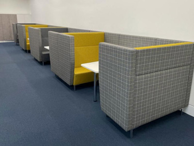 Grey and yellow upholstered booths with side tables in a collaborative work area at Shoreditch Library