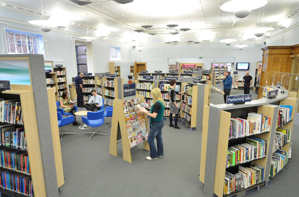 Blue lounge chairs and browsing shelves in a spacious public library area at Gateshead Central Library