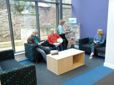 Two upholstered sofas with polka dot patterns and a wooden coffee table in a reading lounge at Thame Library