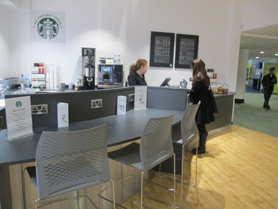 Contemporary café counter with high stools and coffee machines in a library seating area at Boots Library