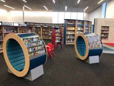 Circular book displays with face-out titles and red seating in a children's reading area at Sherwood Library