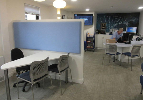 Study tables with grey chairs in a contact area alongside an advice desk at Midsomer Norton Library