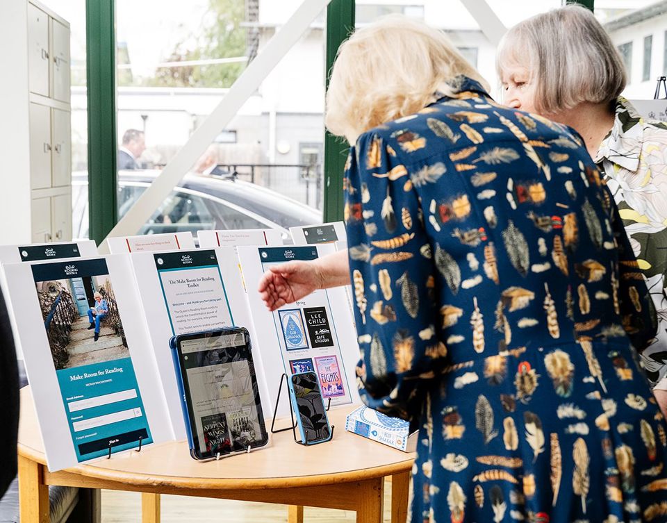 Rachel shows Her Majesty the Toolkit on tablet and phone, with screenshots from the Toolkit in the background.