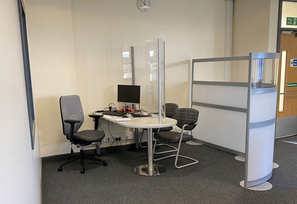 Grey office chairs and a round table with a computer in a private advice desk area at Holt Park Library