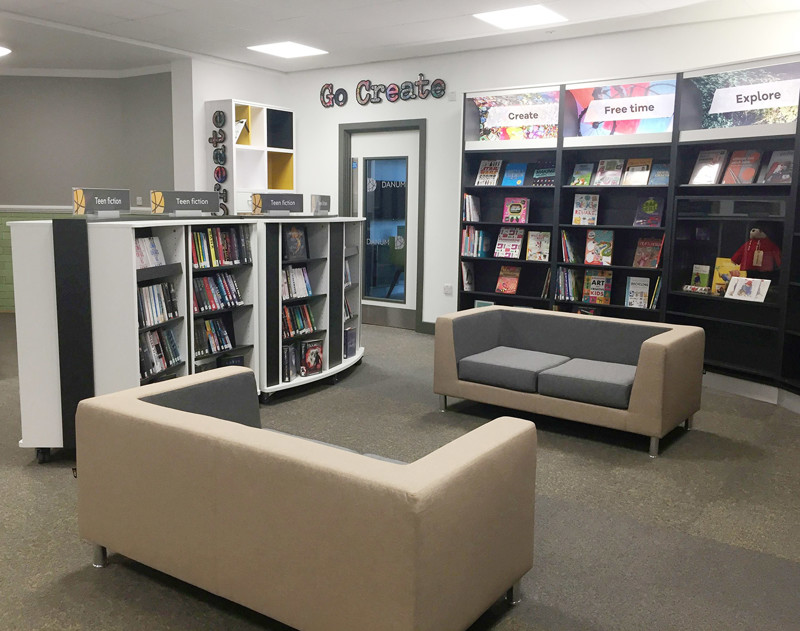 Grey and cream modular sofas beside browsing shelves and themed book displays at Danum Library