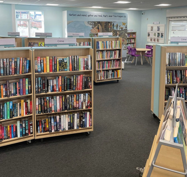 Wooden browser shelving filled with books in the crime section alongside a vibrant purple seating area at Birtley Library