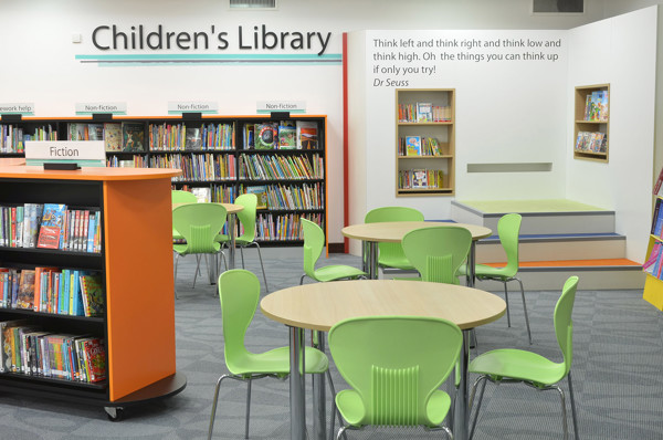 Bright green chairs and round tables in a children's reading area with book displays at Fullwell Cross Library
