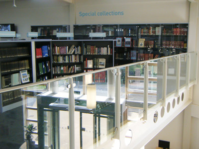 Glass railing overlooking a well-organised special collections area with shelves of books and displays at Worksop Local Studies