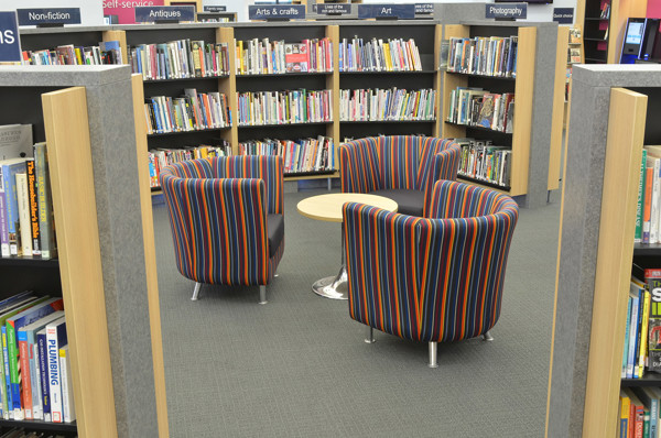 Striped lounge chairs in orange, blue, and green around a circular table in a reading lounge at Gateshead Central Library