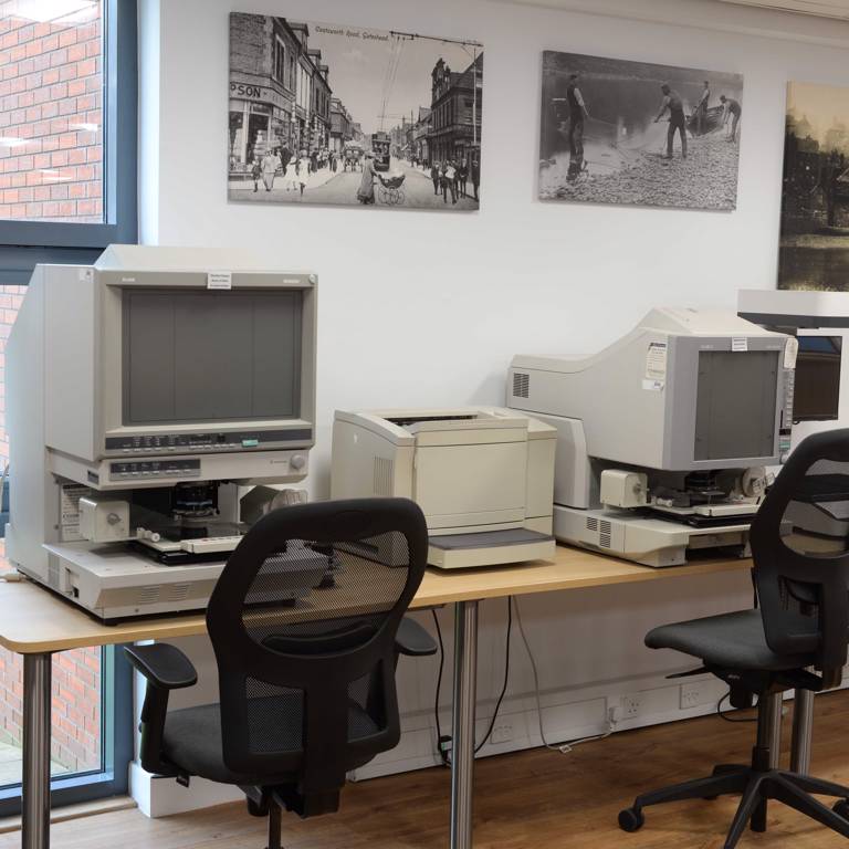 Canvas prints of early photographs decorate walls above microfilm readers