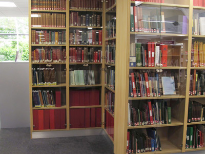 Red and green book collections in glass-fronted shelving units at Newark Local Studies