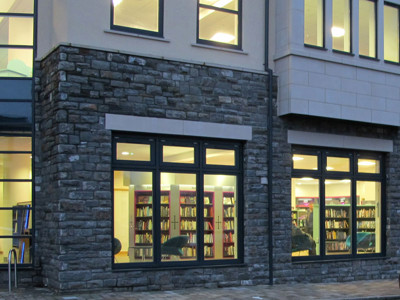 Large windows showcasing browsing shelves and study areas in the newly designed exterior at Caerphilly Library
