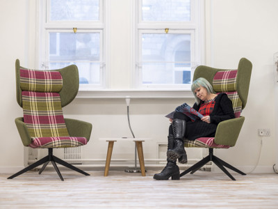 Plaid upholstered high-back chairs and a small side table in a quiet reading space at BIPC Leeds