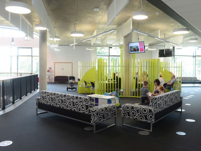 Circular patterned sofas and bright green partitioning in a public library browsing area at Southwater Library