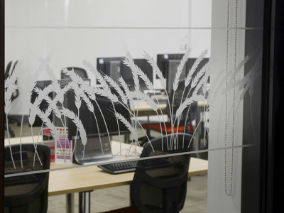 Frosted glass featuring wheat designs in front of study tables and computers at Brackenhurst Campus Library