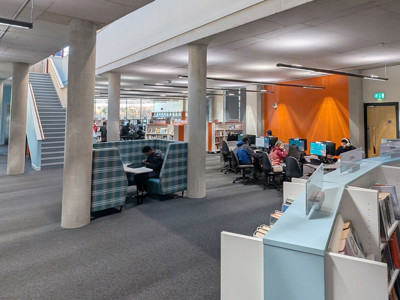 Study seating areas with computer workstations and collaborative booths in a modern open-plan space at Oldham Library