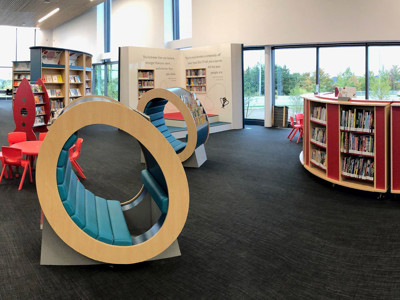 Curved shelving units and circular seating areas in a children's reading space at Sherwood Library