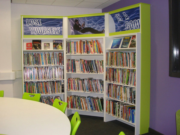 Bright green shelving units filled with books and a graphic display at Werneth School Library