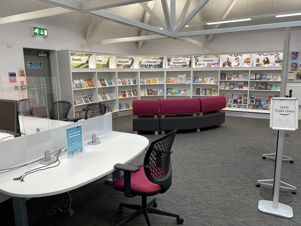 Curved pink seating and browsing shelves filled with magazines in a public library browsing area at Armley Library & Community Hub shared area