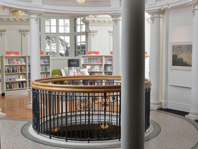 Curved wooden railing and browsing shelves in a circular reading area at Llandudno Library