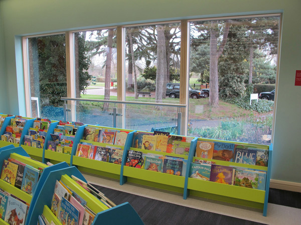 Face-out book displays in bright green beside large windows overlooking the garden at West Bridgford Library