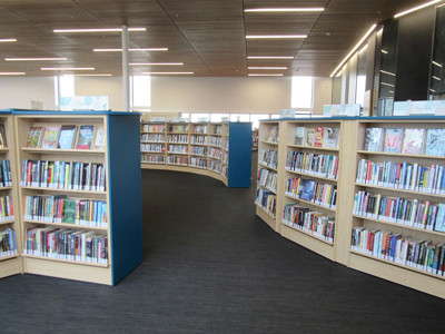Curved wooden bookcases filled with books creating browsing spaces at Sherwood Library