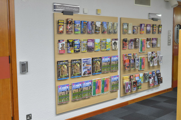 Wall-mounted leaflet displays showcasing a variety of tourist information brochures at Redbridge Central Library