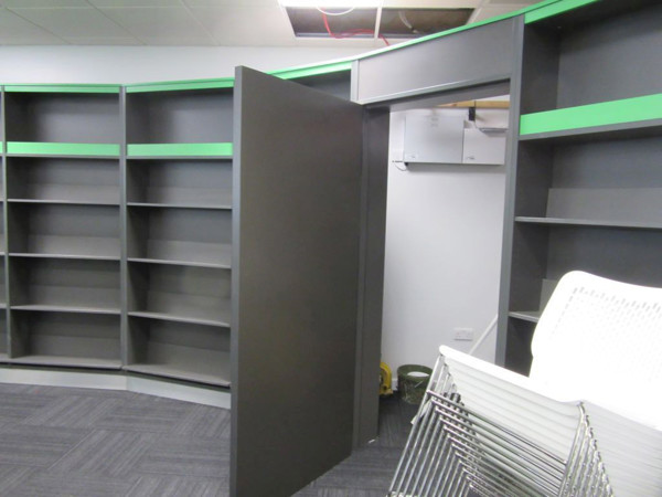Curved grey shelving with green accents and a partially open door in a storage area at Stafford Library