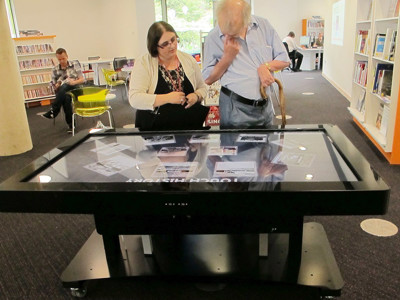 Interactive touchscreen table being used by two patrons in a collaborative browsing space at Southwater Library