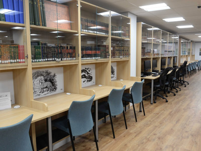 Light blue study chairs and wooden study tables beside computer workstations in a local studies area at Gateshead Archive