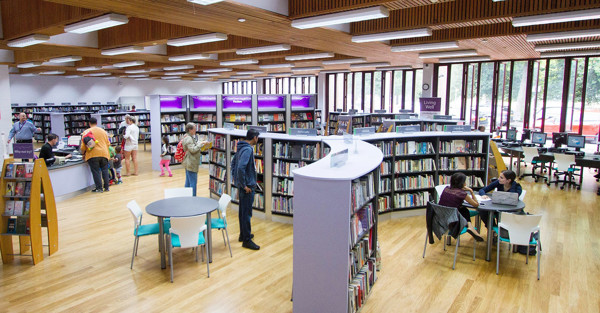 Light wood flooring and modern study tables create an open-plan library seating area at Wanstead Library