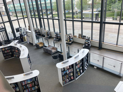 Curved white shelving units with book displays and grey lounge seating in an open-plan library space at Danum Library