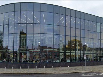 Curved glass façade reflecting the surrounding architecture at Danum Library