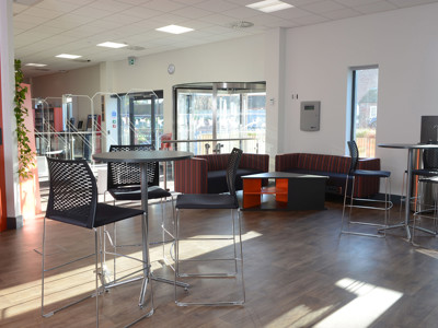 High-top tables and black bar stools beside striped lounge seating in a social area at Brackenhurst Campus Library