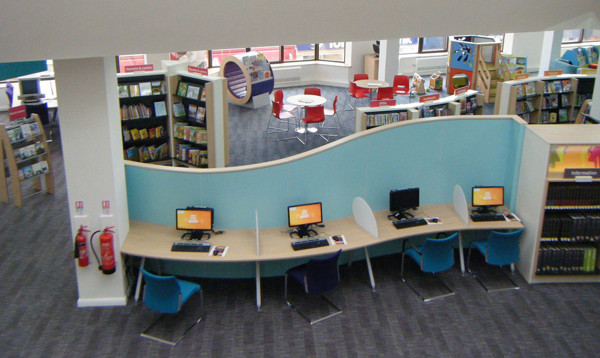 Curved blue partition and computer stations in a public library browsing area at Mansfield Library