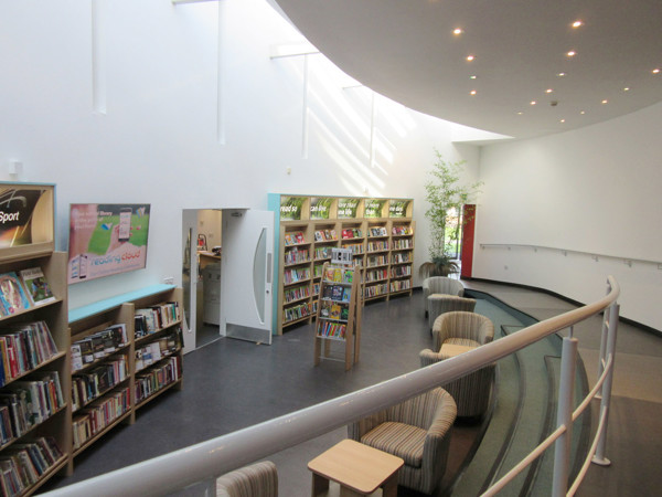Curved shelving filled with books and striped lounge chairs in a young readers' browsing space at Wrekin College Library