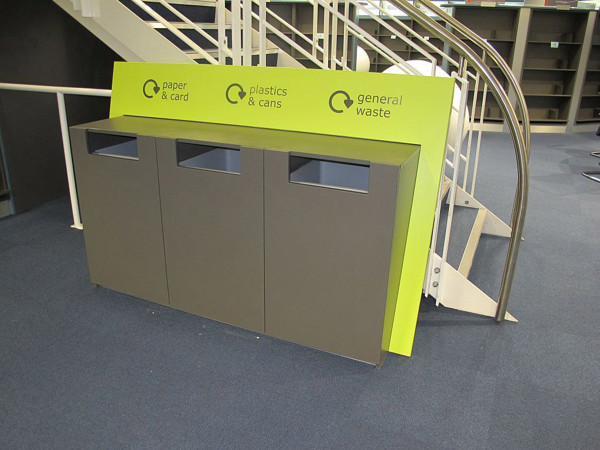 Recycling station with three bins for paper, plastics, and general waste beside a staircase at Boots Library
