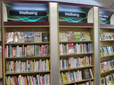 Wellbeing signage above organised shelves filled with health and wellness books at Bicester Library