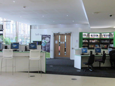 Self-service kiosks and study desks with computers in a digital access area at Stafford Library