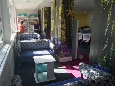Blue upholstered sofas with hexagonal patterns beside a book display in a quiet reading space at Doncaster Deaf School